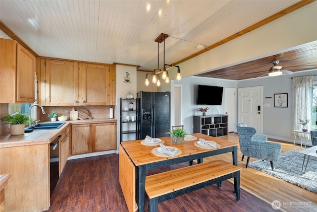 kitchen featuring dark wood finished floors, black appliances, tasteful backsplash, and a sink