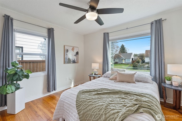 bedroom featuring baseboards, a textured ceiling, ceiling fan, and light wood finished floors