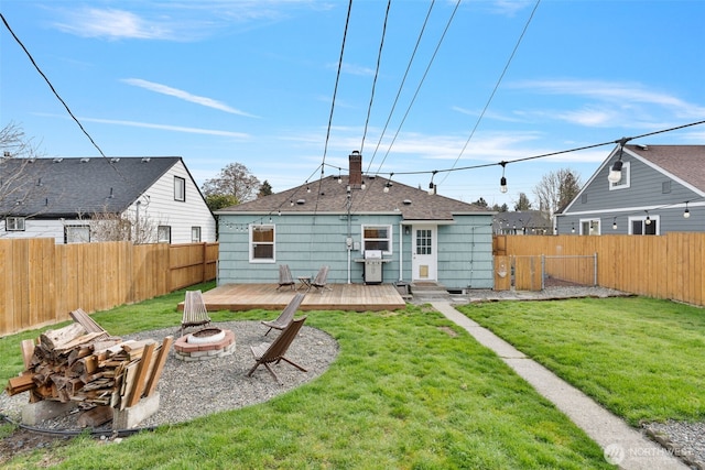 back of house featuring a yard, a fire pit, a fenced backyard, and a chimney