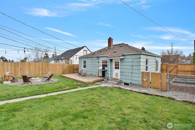 back of house with a wooden deck, an outdoor fire pit, a lawn, a fenced backyard, and a gate