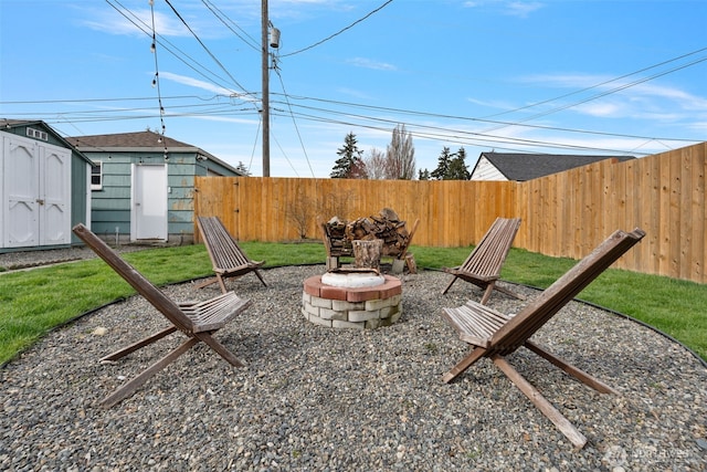 view of yard featuring an outbuilding, a storage shed, fence private yard, and an outdoor fire pit