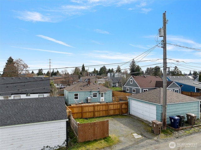 exterior space featuring an outbuilding, a residential view, a detached garage, and fence