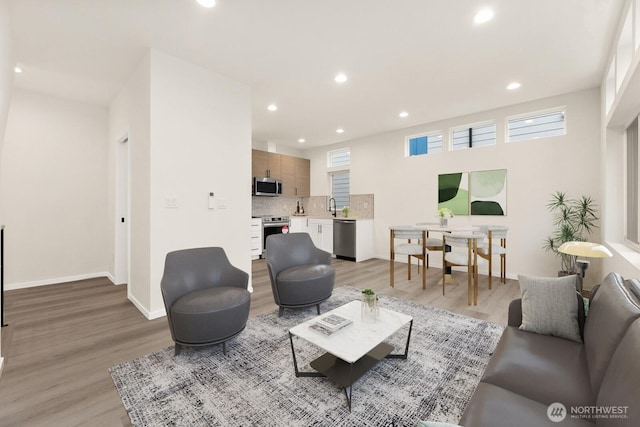 living area with light wood-style floors, recessed lighting, and baseboards