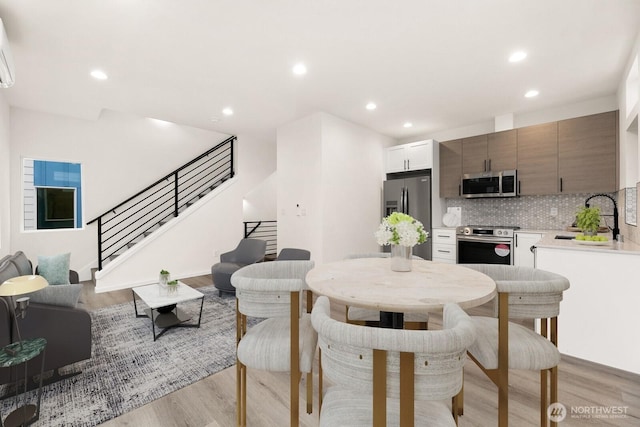 dining space with stairway, recessed lighting, light wood-style flooring, and a wall mounted AC