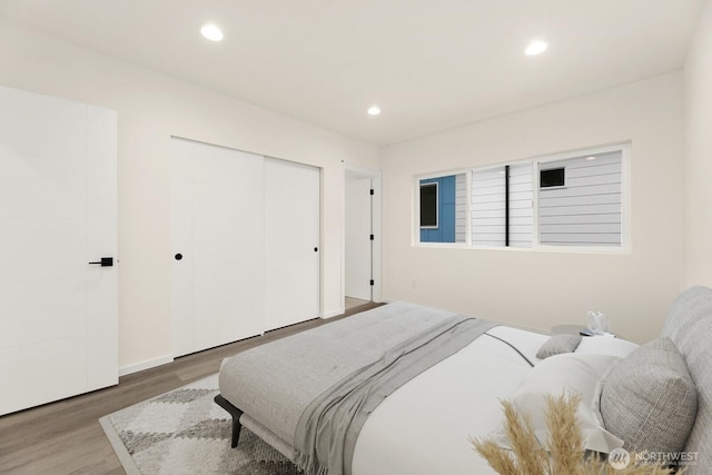 bedroom featuring a closet, wood finished floors, and recessed lighting