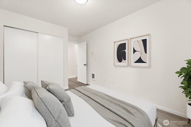 bedroom with baseboards, a closet, visible vents, and dark wood-type flooring