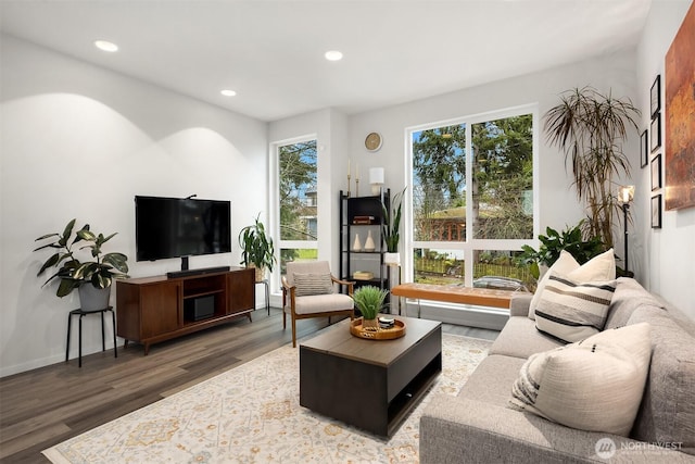 living area with baseboards, wood finished floors, and recessed lighting