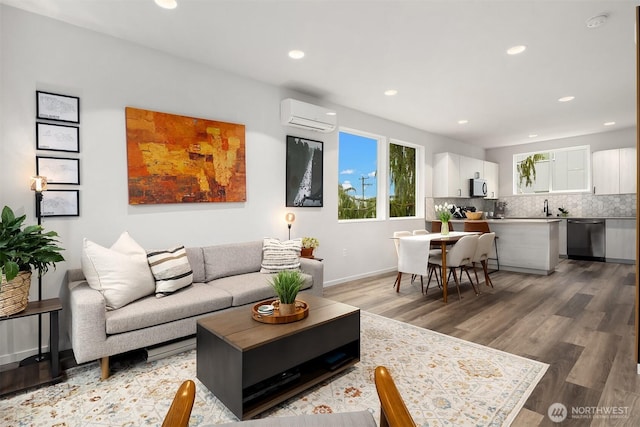 living area featuring recessed lighting, baseboards, a wall mounted air conditioner, and light wood finished floors