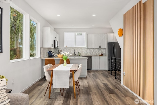 kitchen with appliances with stainless steel finishes, white cabinets, dark wood finished floors, and decorative backsplash