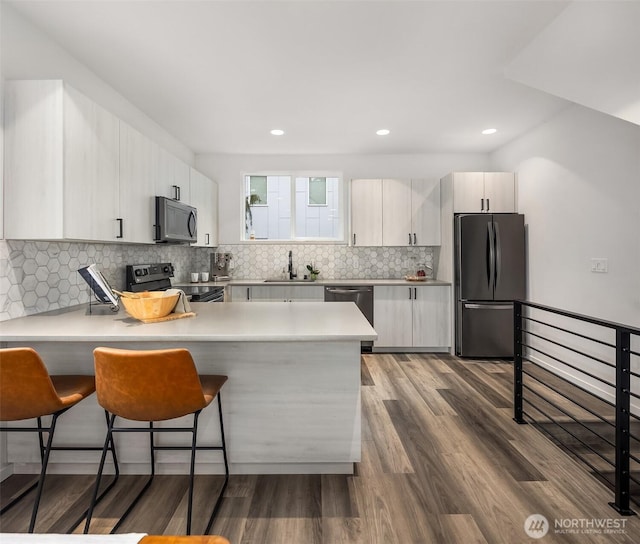 kitchen with dark wood-style flooring, freestanding refrigerator, a peninsula, black range with electric cooktop, and a sink