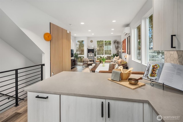 kitchen with recessed lighting, white cabinetry, an AC wall unit, light wood-type flooring, and backsplash