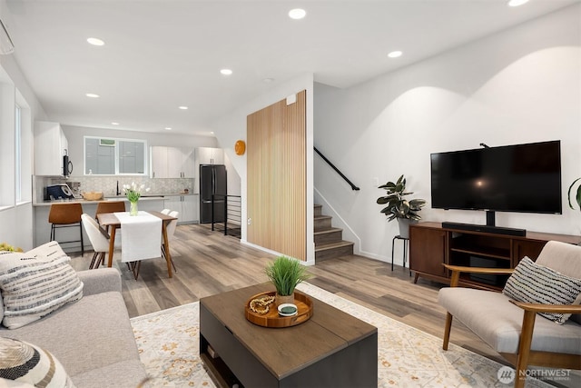 living area with stairs, light wood finished floors, baseboards, and recessed lighting