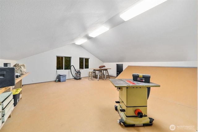 recreation room with lofted ceiling, a textured ceiling, and carpet flooring