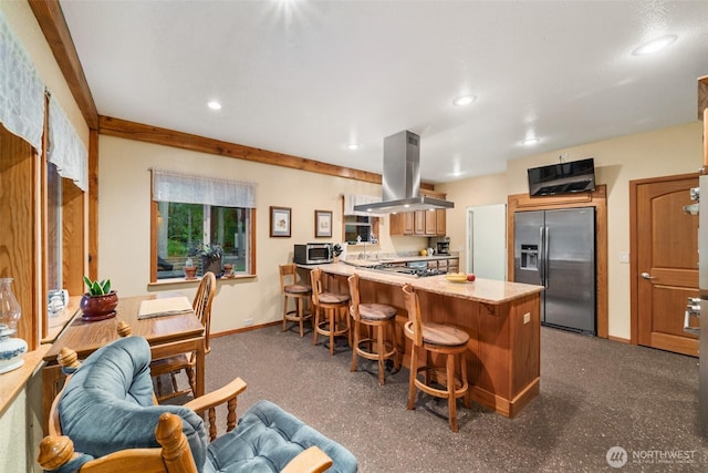 kitchen with appliances with stainless steel finishes, a kitchen breakfast bar, a peninsula, island exhaust hood, and light countertops