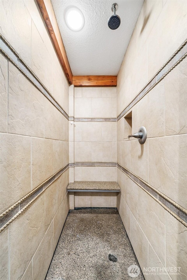 full bath with tiled shower and a textured ceiling