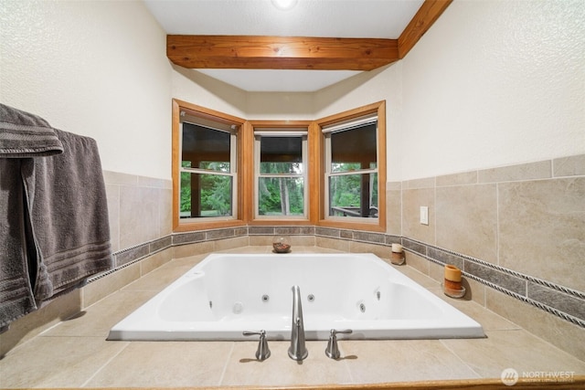 bathroom featuring beamed ceiling and a tub with jets