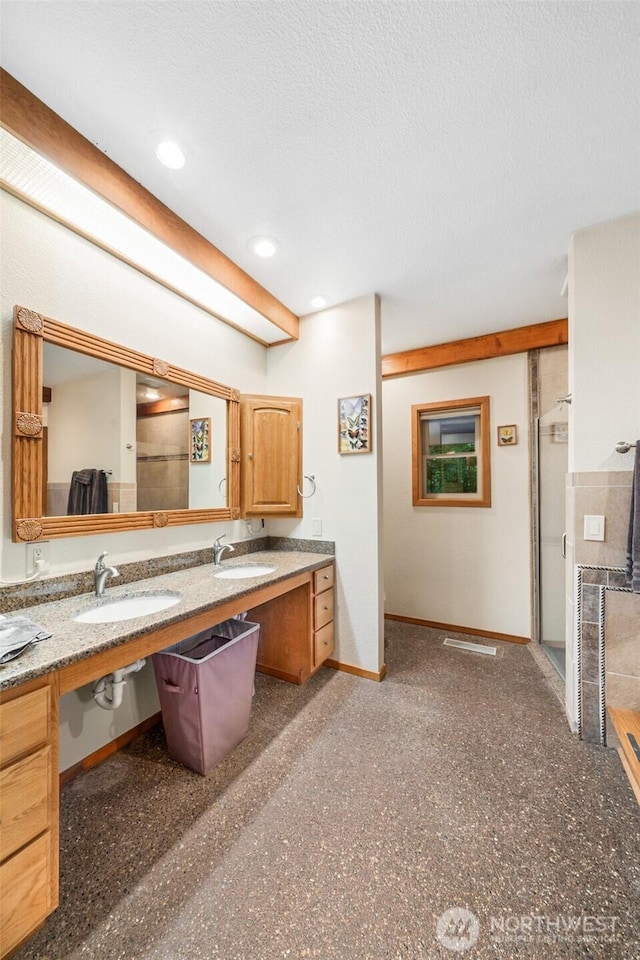 full bath with a stall shower, a textured ceiling, baseboards, and a sink