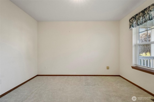 spare room with light colored carpet and baseboards