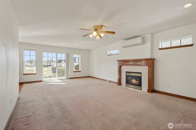 unfurnished living room with a tiled fireplace, a wall mounted air conditioner, light colored carpet, and baseboards