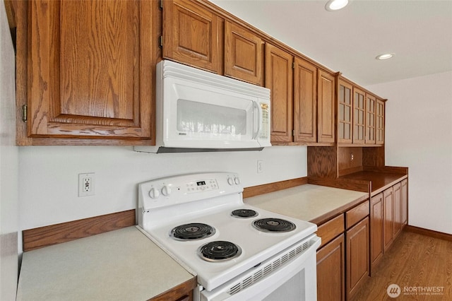 kitchen with recessed lighting, white appliances, baseboards, light wood-type flooring, and brown cabinetry