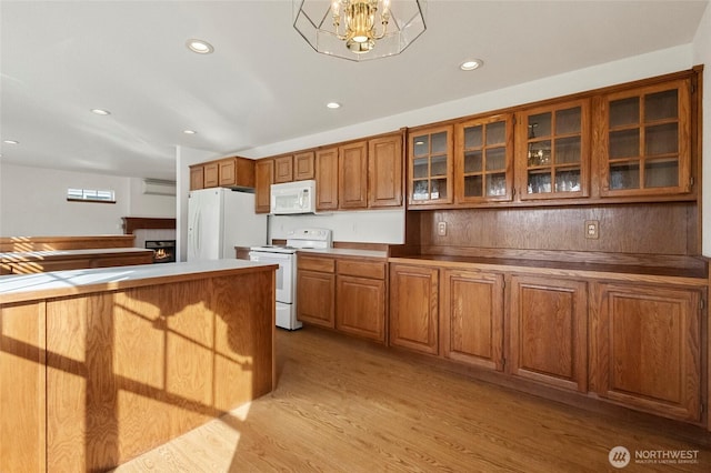 kitchen with brown cabinetry, glass insert cabinets, light wood-type flooring, white appliances, and a lit fireplace