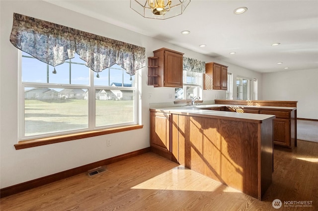 kitchen featuring visible vents, dark wood finished floors, a peninsula, and baseboards