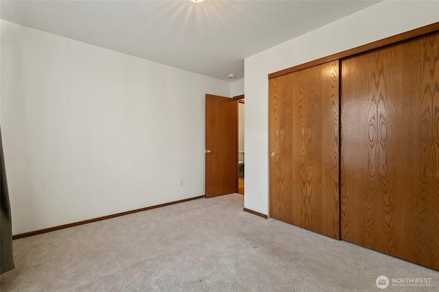 unfurnished bedroom with carpet floors, a closet, and baseboards