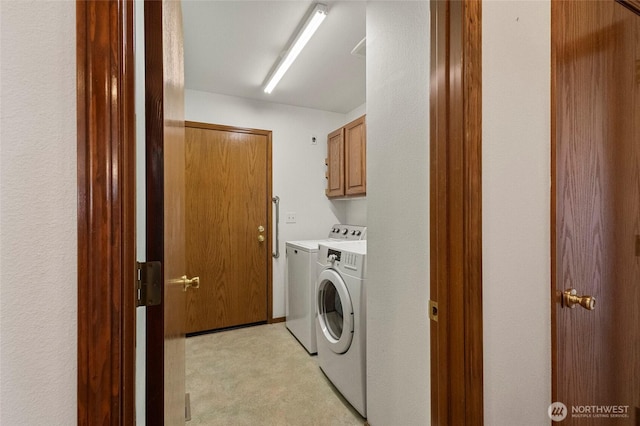 clothes washing area with washer and dryer and cabinet space