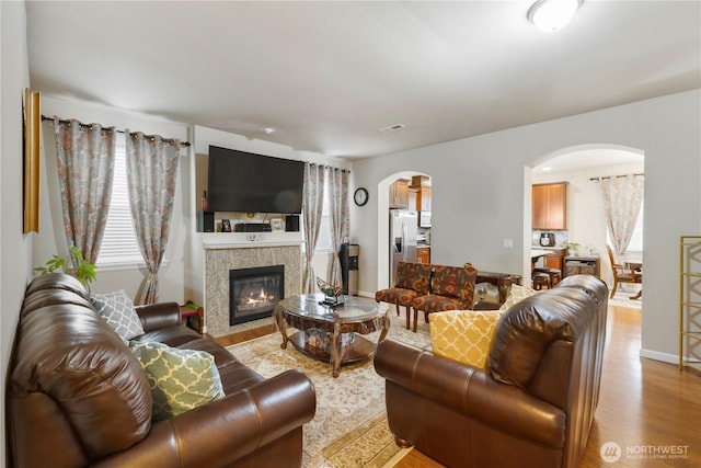 13019 SE 309th Pl, Auburn, WA 98092 - living room featuring arched walkways, visible vents, light wood-style flooring, and a tiled fireplace