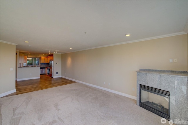 unfurnished living room with ornamental molding, a glass covered fireplace, and baseboards