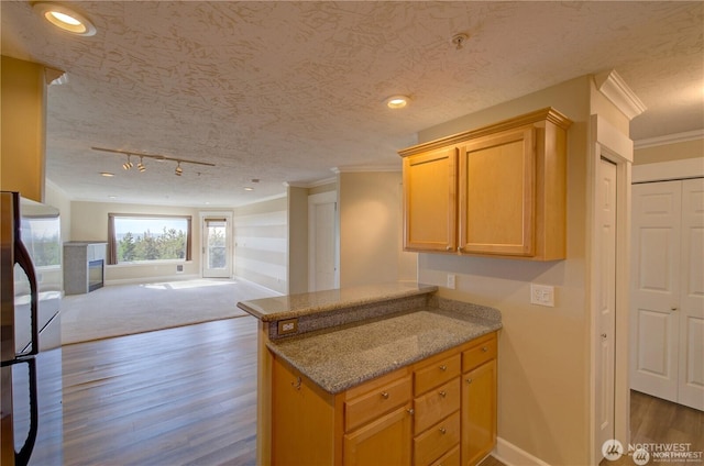 kitchen with a peninsula, ornamental molding, open floor plan, and a textured ceiling