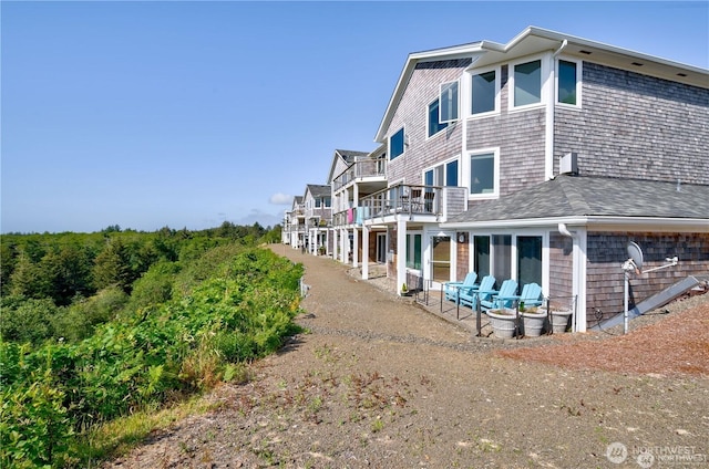 exterior space with a shingled roof and a balcony