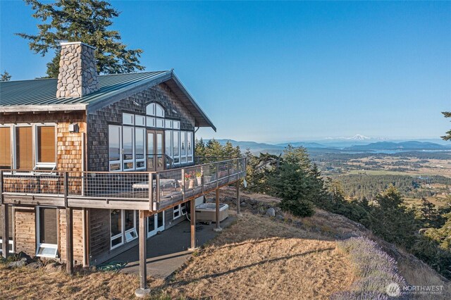 312 Stormridge Rd, Friday Harbor, WA 98250 - view of side of home with a chimney, a deck with mountain view, and metal roof