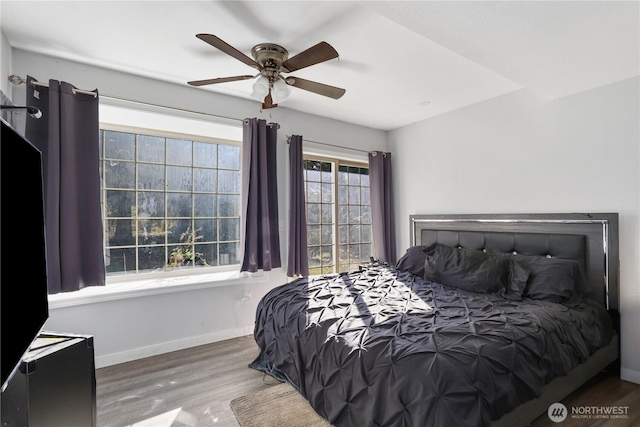 bedroom featuring a ceiling fan, baseboards, and wood finished floors