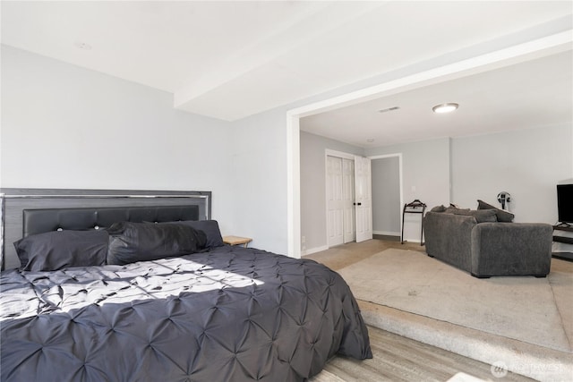 bedroom with light wood finished floors, visible vents, and baseboards