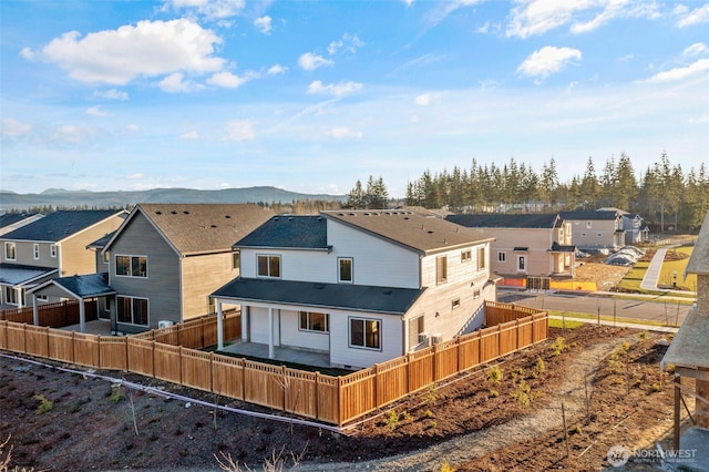 back of house featuring a mountain view, a fenced backyard, and a residential view