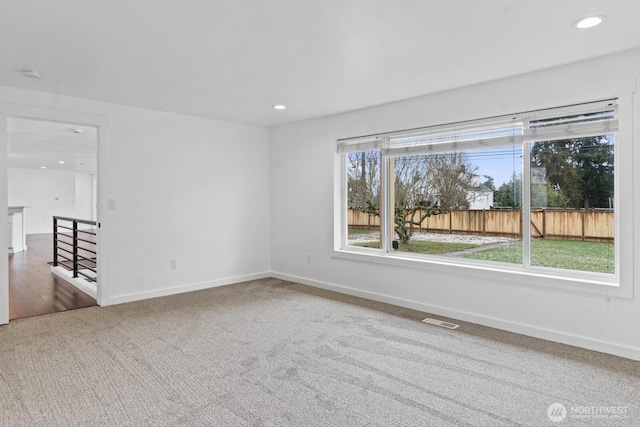 spare room with recessed lighting, carpet flooring, visible vents, and baseboards