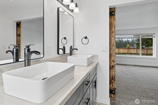 bathroom featuring double vanity, baseboards, and a sink