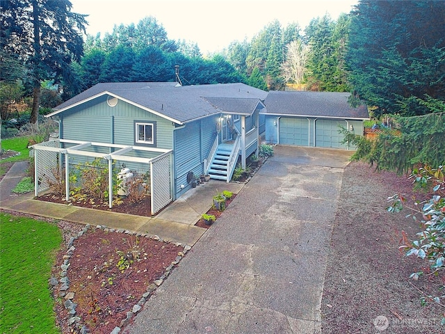 view of front of house with driveway, a garden, stairway, and a shingled roof