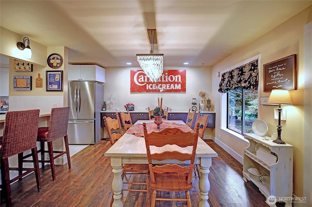 dining area featuring dark wood-style flooring, baseboards, and an inviting chandelier