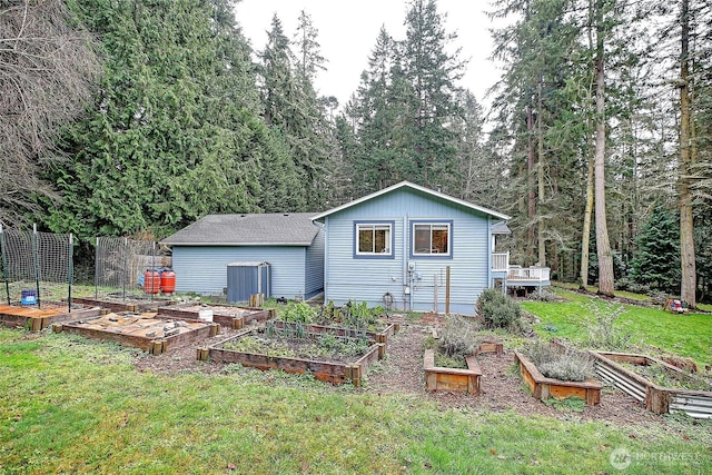 rear view of house featuring a vegetable garden and a yard