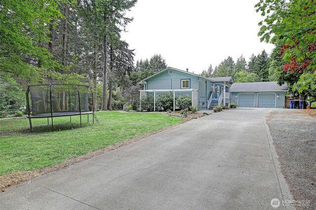 3045 Mabana Heights Rd, Camano Island, WA 98282 - view of front of house featuring a trampoline, concrete driveway, a front lawn, and a garage