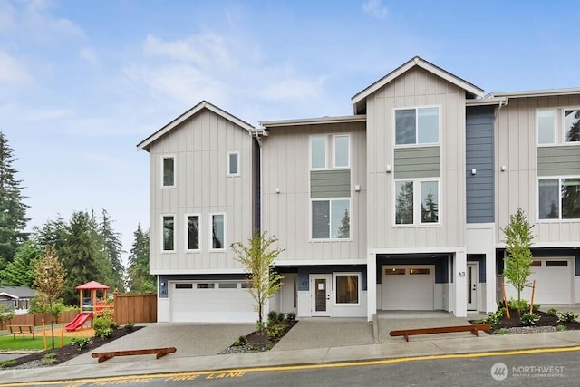 view of front of property with an attached garage, driveway, board and batten siding, and a playground