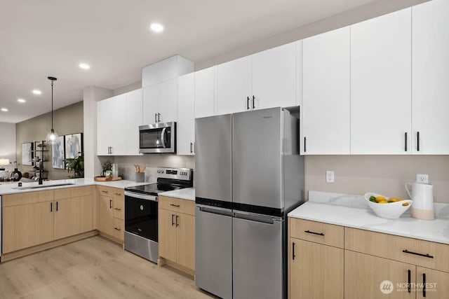 kitchen featuring white cabinets, appliances with stainless steel finishes, light countertops, and a sink