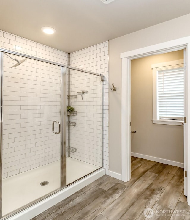 bathroom with a shower stall, baseboards, and wood finished floors