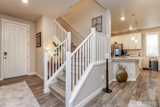 stairs with recessed lighting, visible vents, baseboards, and wood finished floors