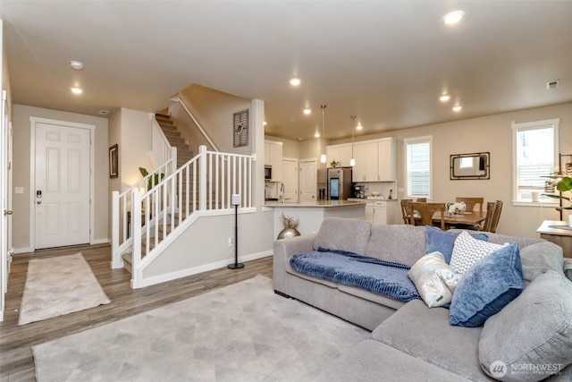 living room with light wood-style flooring, stairs, visible vents, and recessed lighting