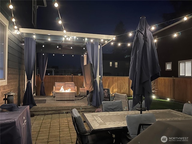 patio at twilight featuring fence, a fire pit, and outdoor dining area