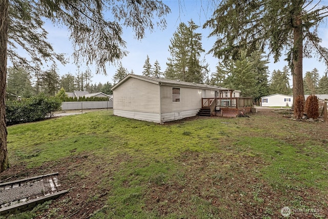 rear view of property featuring a deck, a yard, and fence