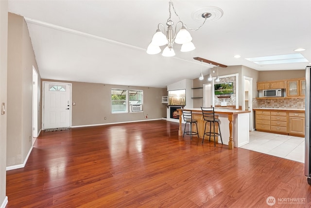 interior space with lofted ceiling with skylight, baseboards, light wood finished floors, and cooling unit